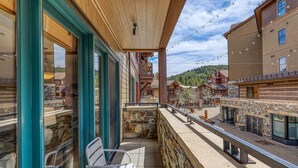 A balcony with stone walls, wooden beams, and metal railings. - Iron Horse Lodge North 206 - delightful slopeside (Truckee)