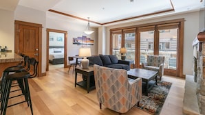 A spacious living area with a high ceiling, a dining area with a bar, and large windows offering a view of the city. - Iron Horse Lodge North 206 - delightful slopeside (Truckee)