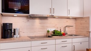 Een moderne keuken met witte kasten, roestvrijstalen apparatuur en een houten spatwand.