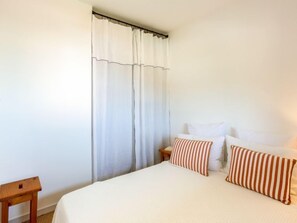 Une chambre à coucher avec un grand lit, des rideaux blancs et des coussins à rayures.