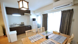 Una cocina compacta con electrodomésticos modernos, un comedor con individuales a rayas y grandes ventanales con cortinas.