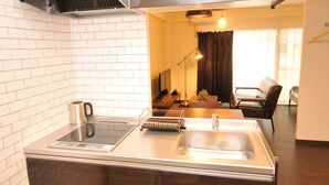A compact kitchen with a built-in stove, a coffee maker, and a sink. - Maison Milano Nakatsu Apartment (Osaka)