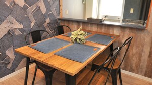 A dining area with a wooden table, black chairs, and a hanging light fixture. - Maison Milano Nakatsu Apartment (Osaka)