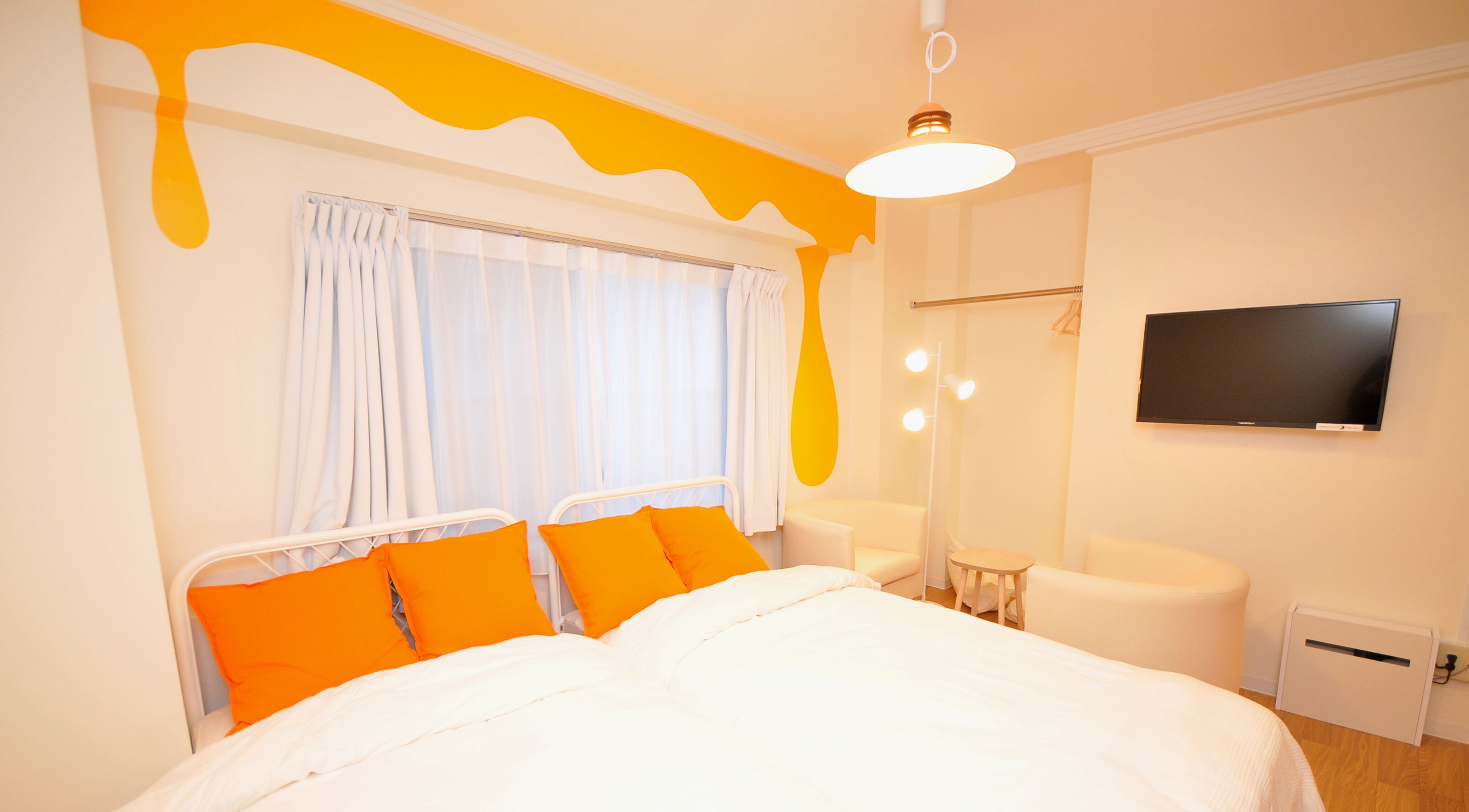 A hotel room with a bed, a TV, a chair, a desk, and a mirror.