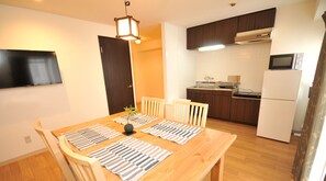 Una cocina compacta con zona de comedor, muebles de madera y un televisor de pantalla plana montado en la pared.