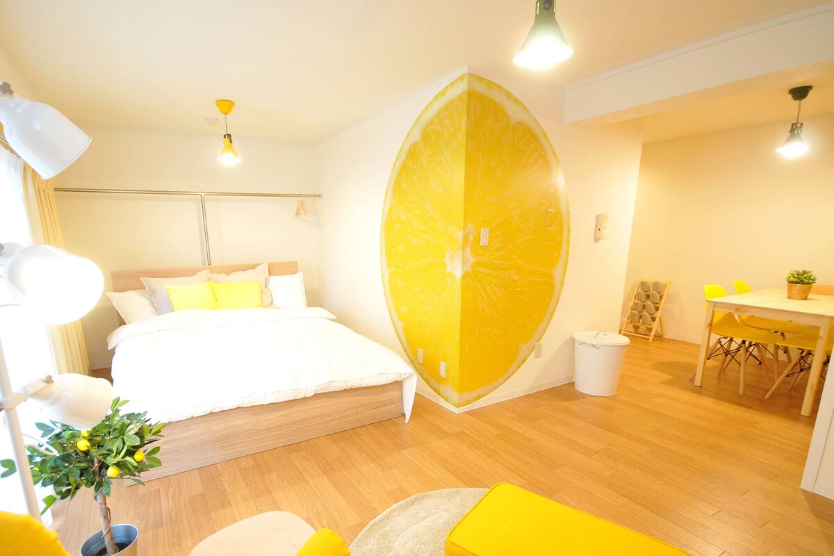 Habitación de hotel moderna con una cama grande, una pared amarillo brillante y una decoración original con una rodaja de limón.