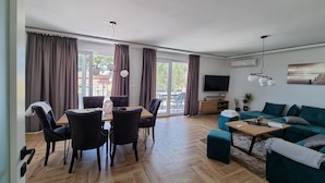 Amplia sala de estar con mesa de comedor, sillas, sofá y televisor.