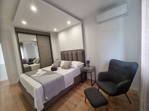 A modern bedroom with a bed, bedside table, chair, and a large mirror. - Villa Lea (Kastela)