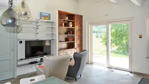 A living room with a TV, a wooden cabinet, and a sliding glass door to the outdoors.
