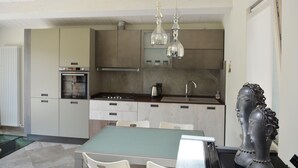 A modern kitchen with a central island, stainless steel appliances, and pendant lighting.
