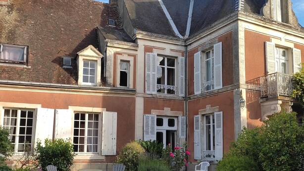 A two-story house with a garden patio, white outdoor furniture, and a stone fountain. - Village property in the Perche region with basic shops and SNCF train station. (Sablons sur huisne)