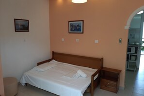 A neatly made bed with white linens, a wooden headboard, and a small wooden nightstand with drawers. - Amazing apartment in Mpenitses with terrace (Mpenitses)