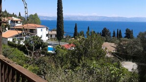 A coastal residential area with houses, a pool, and a view of the sea and mountains.