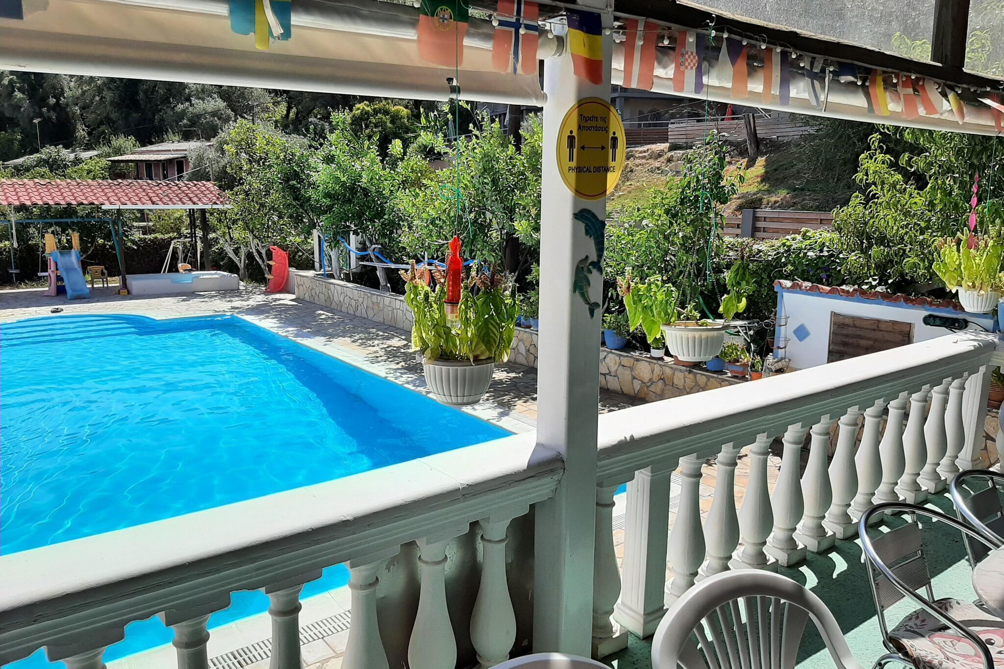 Zwembadgedeelte met een helderblauw zwembad, een witte balustrade en potplanten.