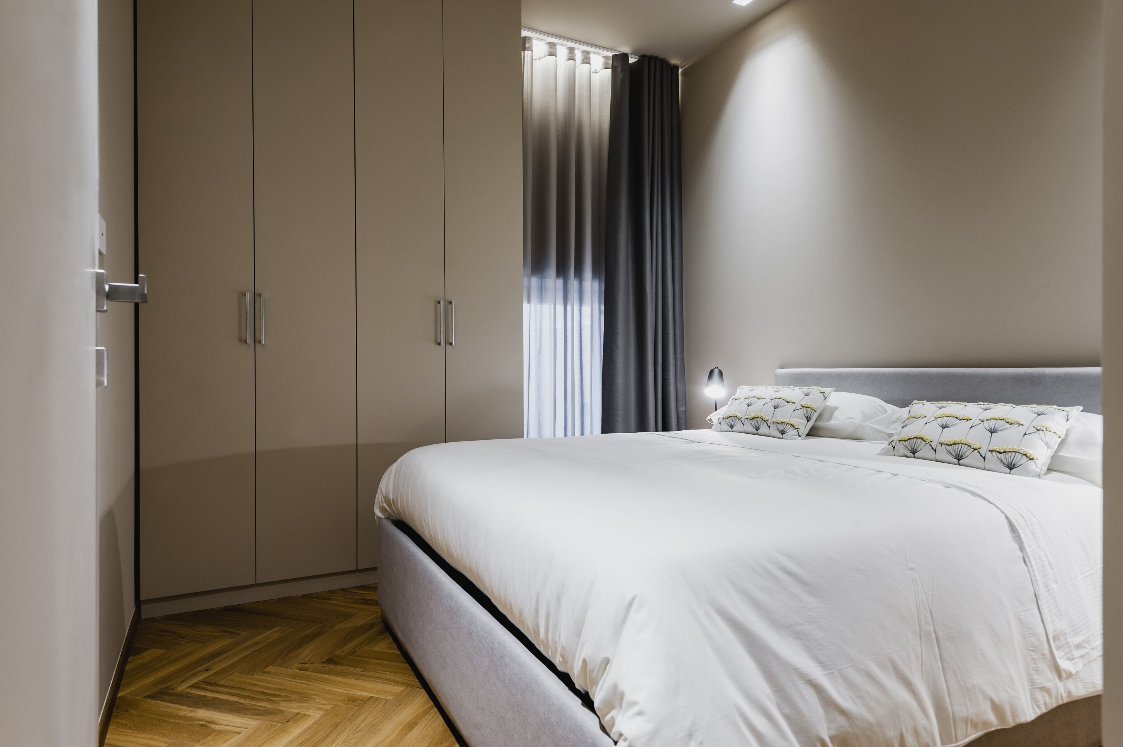 A bedroom with a bed, a wardrobe, and a window with curtains.