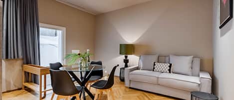 Ett modernt vardagsrum med en soffa, ett matbord, stolar och en lampa.