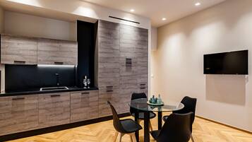 Una cocina moderna con estufa integrada, armarios negros y un comedor con mesa de vidrio y sillas negras.