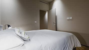 Un dormitorio con cama, mesita de noche, lámpara y puerta.