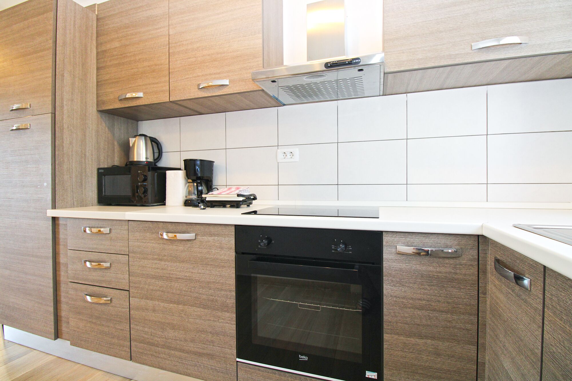A modern kitchen with wooden cabinets, a built-in oven, a coffee maker, and a microwave.