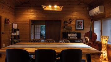 A wooden interior with a long dining table, black chairs, a cros