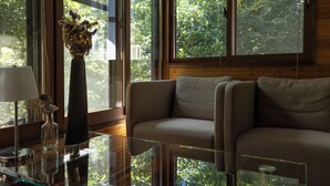 A room with a glass coffee table, a sofa, a lamp, and a vase with flowers. - Azumino Salon (Azumino)
