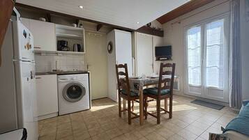 Une cuisine compacte équipée d’un lave-linge, d’un réfrigérateur et d’un coin repas avec une table et des chaises.