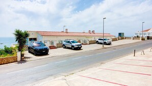 A coastal hotel with a red-tiled roof, a parking lot, and a view of the sea. - COSTA 2 5 Roses - Immo Barneda (Rosas / Roses)