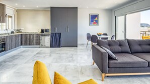 A modern kitchen with a dining area, a sofa, and a view through a glass door. - COSTA 2 5 Roses - Immo Barneda (Rosas / Roses)