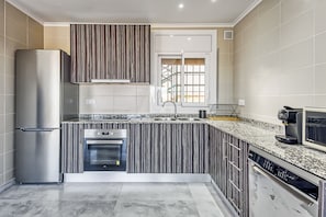 A modern kitchen with a stainless steel refrigerator, a built-in oven, and a dishwasher.