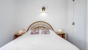 A neatly made bed with a woven headboard, two bedside lamps, and a wall-mounted light fixture. - COSTA 2 5 Roses - Immo Barneda (Rosas / Roses)
