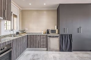 Una cocina moderna con horno integrado, microondas y lavavajillas, que presenta un salpicadero a rayas y armarios grises.