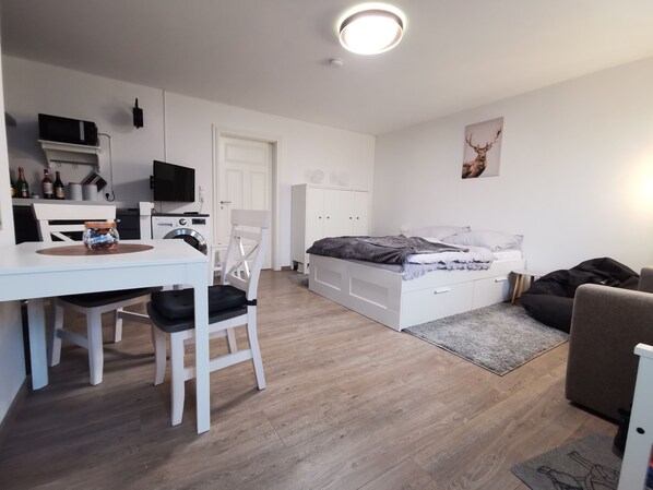 Quarto moderno e bem iluminado, com cama, escrivaninha e cadeira.
