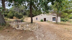 Une maison en pierre avec un petit porche et une table entourée de chaises.