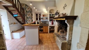 Une cuisine dotée d’un four en pierre, d’un escalier en bois et d’un sol carrelé.