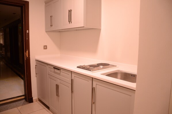 A kitchen with white cabinets, a stainless steel sink, and a countertop. - Artal Taibah Hotel (Madinah)
