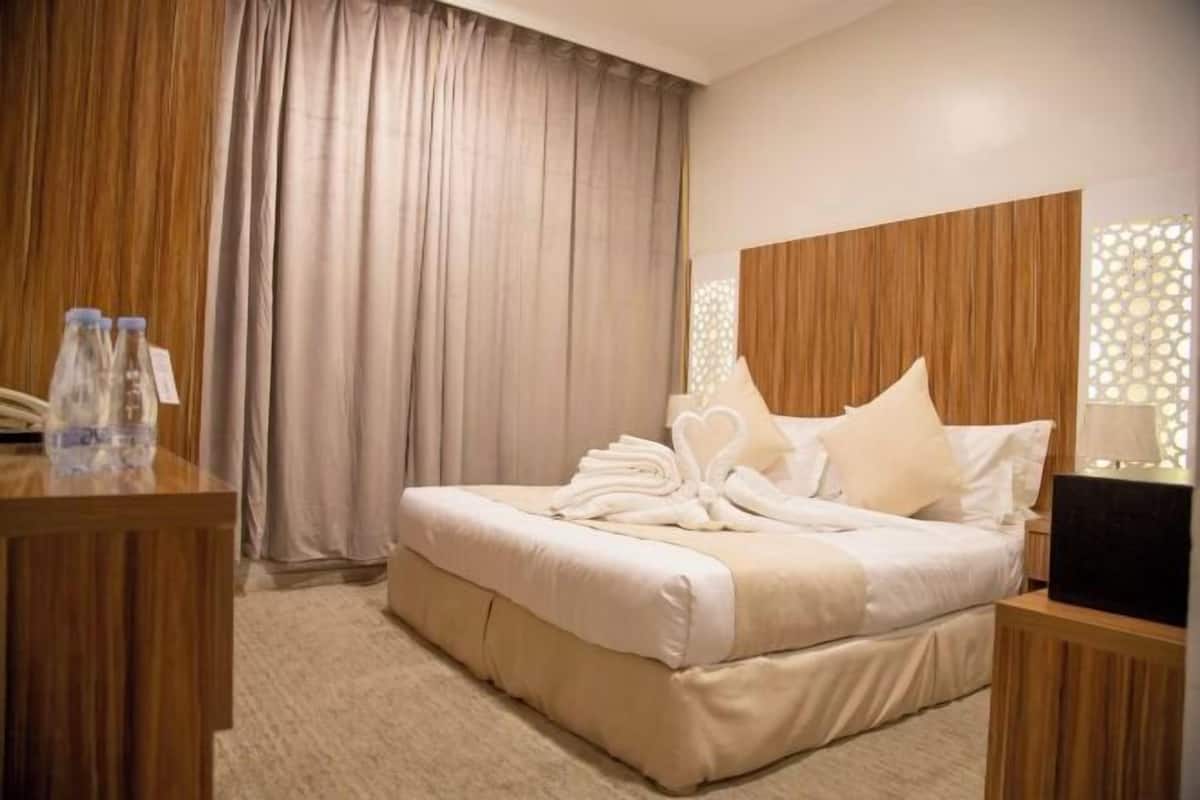 A hotel room with a bed, a desk with a lamp, a telephone, and a curtain.