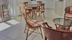 A spacious living area with a dining set, wicker chairs, and a glass-top coffee table. - Charming, bright house 10 minutes from the village center (Collioure)