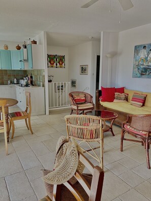 A spacious living area with wicker furniture, a dining table, and a kitchen in the background.
