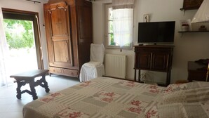 Une chambre à coucher avec un lit, une armoire en bois, un téléviseur et une fenêtre avec des rideaux.