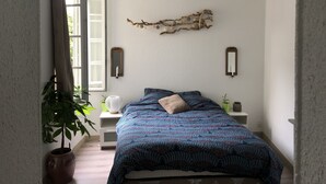 A bedroom with a bed, a potted plant, a wall-mounted mirror, and a decorative branch. - ?appartement Futuroscope T2 ? Cosyhousebyjanna? (POITIERS)