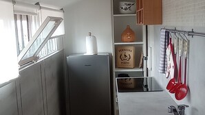 A compact kitchen with a refrigerator, a sink, and a window with blinds. - Attic apartment iPatrizi (Moncalieri)