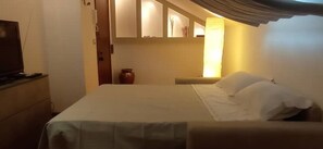 A hotel room with a bed, a television, and a vase on a nightstand. - iPatrizi Attic Apartment (Moncalieri)