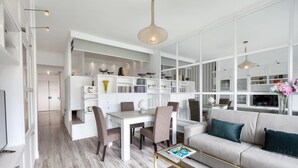 A modern living room with a dining area, white walls, and a large window. - Bed and Breakfast Sorrento 7 Flat (Sorrento)