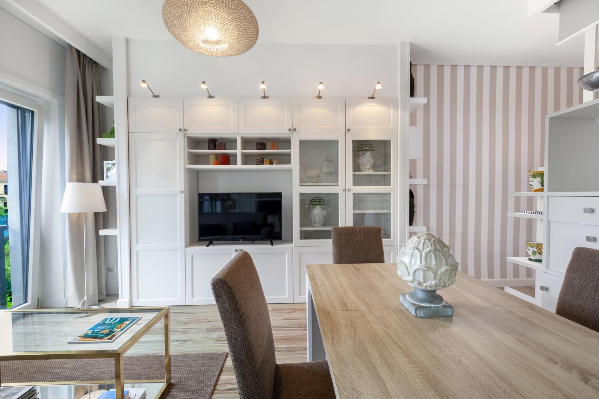 Un salon moderne avec une table basse en verre, une table à manger en bois et un téléviseur.