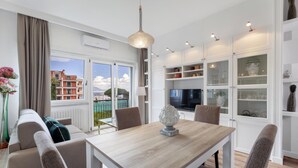 A modern dining area with a wooden table and chairs, a decorative centerpiece, and a view of buildings through large windows. - Bed and Breakfast Sorrento 7 Flat (Sorrento)