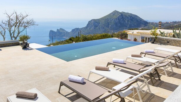 An infinity pool with lounge chairs and a view of the sea and mountains. - Villa Ligea in Sant Agata sui Due Golfi (Massa Lubrense)