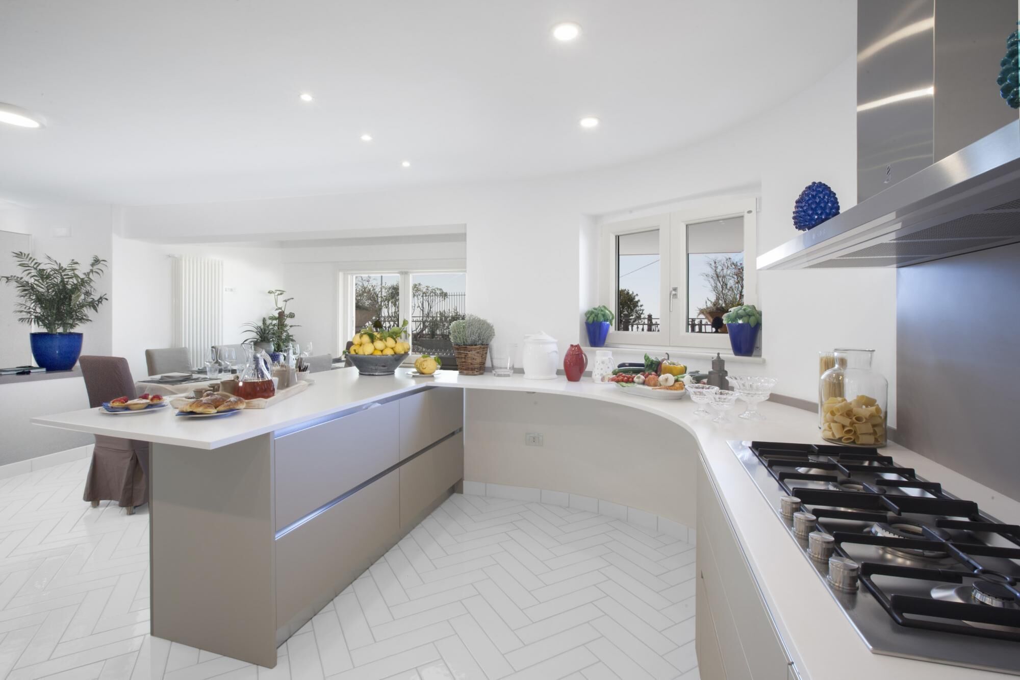 A modern kitchen with a central island, stainless steel appliances, and a herringbone tile floor.