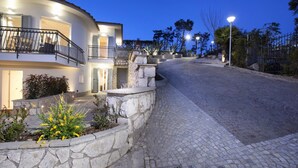 A curved building with a stone retaining wall and a paved street. - Villa Ligea in Sant Agata sui Due Golfi (Massa Lubrense)