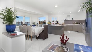 A modern kitchen with a central island, white cabinetry, and a view to the outside. - Villa Ligea in Sant Agata sui Due Golfi (Massa Lubrense)