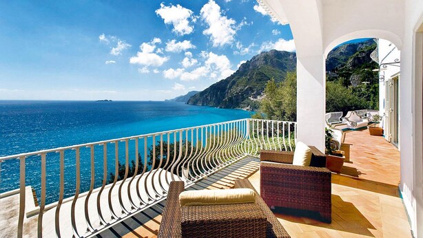 A balcony with a view of the sea and mountains, wicker furniture, and a white railing. - Villa Le Sirene in Positano (Positano)
